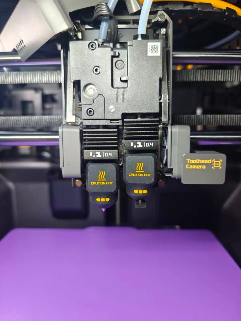 Bambu Lab X2D dual nozzle with Toolhead Camera close-up on purple print bed