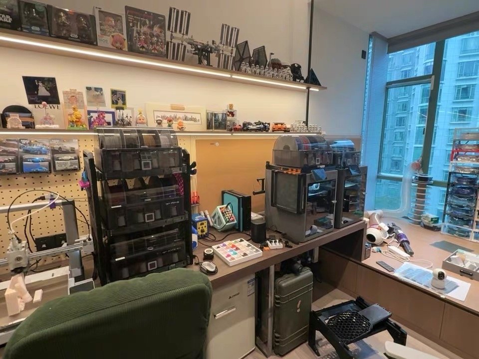 How to Choose a 3D Printer: A Beginner's Buyer's Guide (2026) 8 A real maker workspace with several 3D printers, filament storage bins, and printed models on shelves