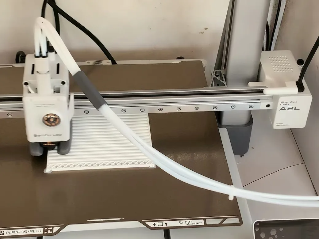 Bambu Lab A2L Review: Is the Big Bed Slinger Worth It? (2026) 6 Bambu Lab A2L print head laying down white filament on the textured bed, A2L branding visible