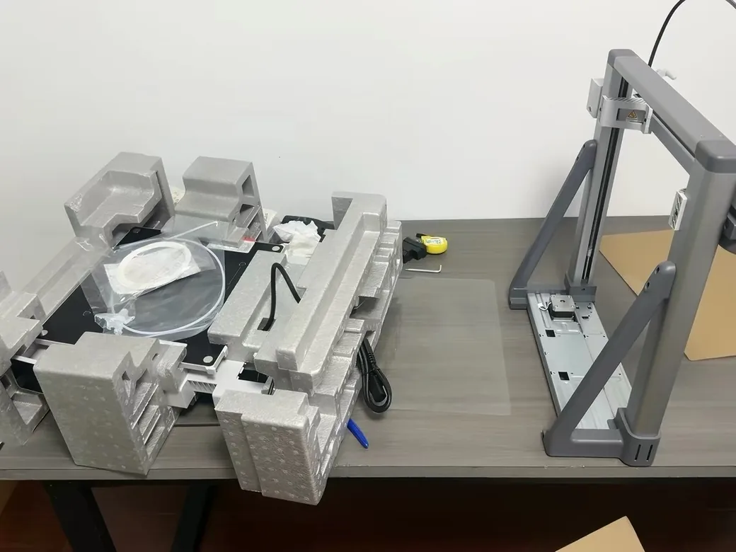 Bambu Lab A2L Review: Is the Big Bed Slinger Worth It? (2026) 4 Bambu Lab A2L box contents laid out on a desk, gantry, foam, accessories and build plate