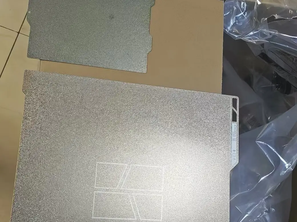 Two textured PEI build plates sitting in a box.