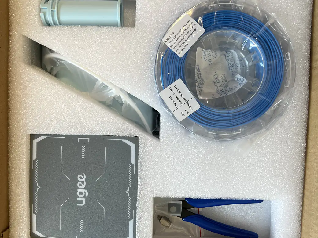 ugee Funbox 3D Printer Review: I Gave It to a 6-Year-Old for a Week 6 ugee Funbox accessories in foam: blue PLA spool, pliers, cleaning needle and magnetic build plate