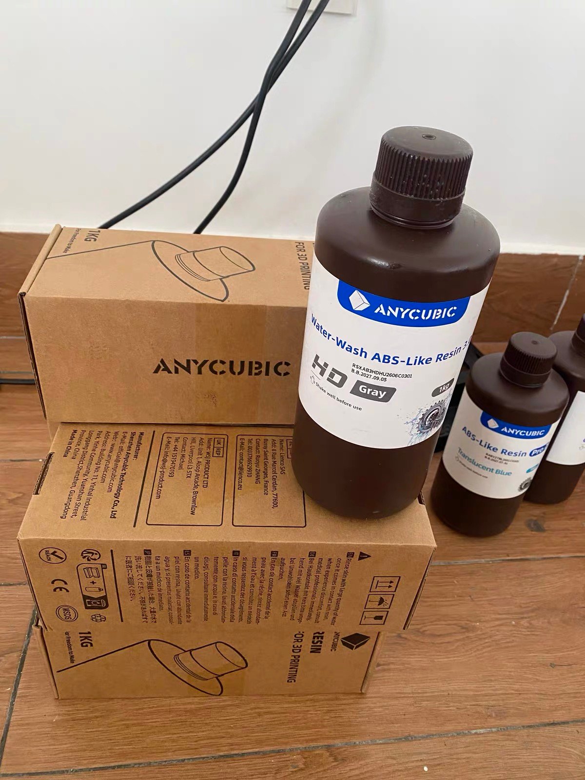 The Difference Between ABS-Like and Standard Resin (What the Tests Actually Show) 8 Anycubic Water-Wash ABS-Like Resin 3.0 and ABS-Like Resin Pro bottles beside their 1kg boxes.