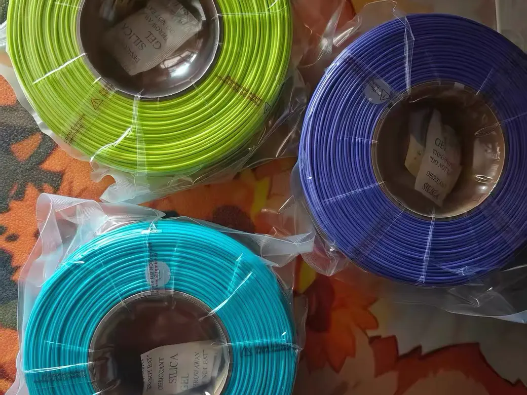 Filament Storage Ideas: 6 Setups Ranked by Cost, Capacity, and What They Don't Fix 4 Three filament spools sealed in clear bags, each with a silica gel desiccant packet inside the hub