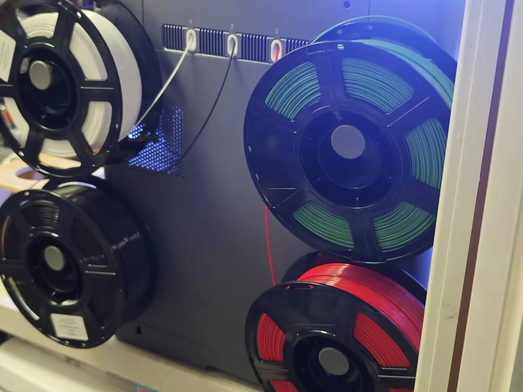 Four filament spools on the Flashforge Creator 5's simple side pegs feeding into numbered manual load ports