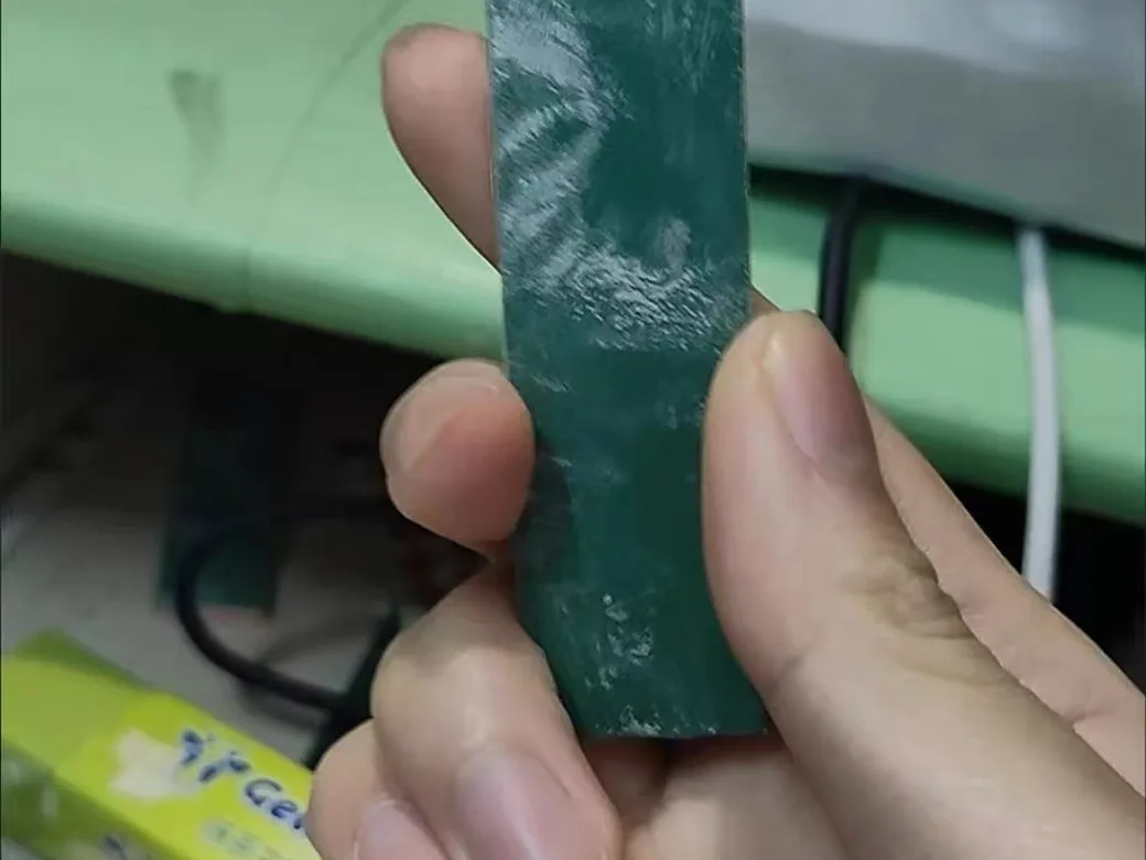 A sanding stick loaded with white plastic residue after use