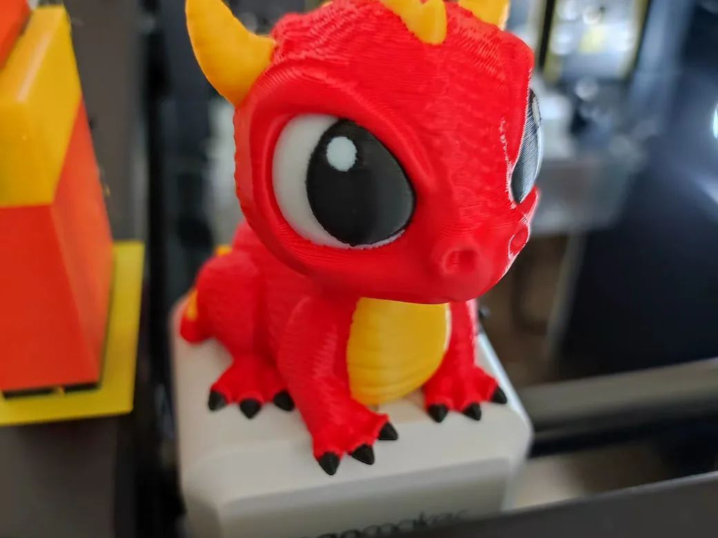 Red, yellow and black multicolor dragon model printed on the Snapmaker U1, sitting in front of the toolhead dock
