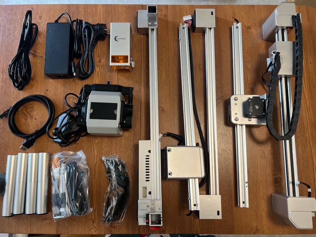 Carverall X1Pro Unboxing: Specs, Price, and What's in the Box (2026) 6 All Carverall X1Pro parts laid out: gantry rails, laser head module, power adapter, height risers, air assist pump, safety glasses, and cabling