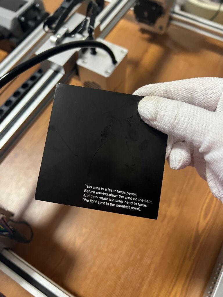 Carverall X1Pro Unboxing: Specs, Price, and What's in the Box (2026) 15 Carverall X1Pro laser focus test card held up in front of the assembled machine, with instructions for finding the smallest focus point