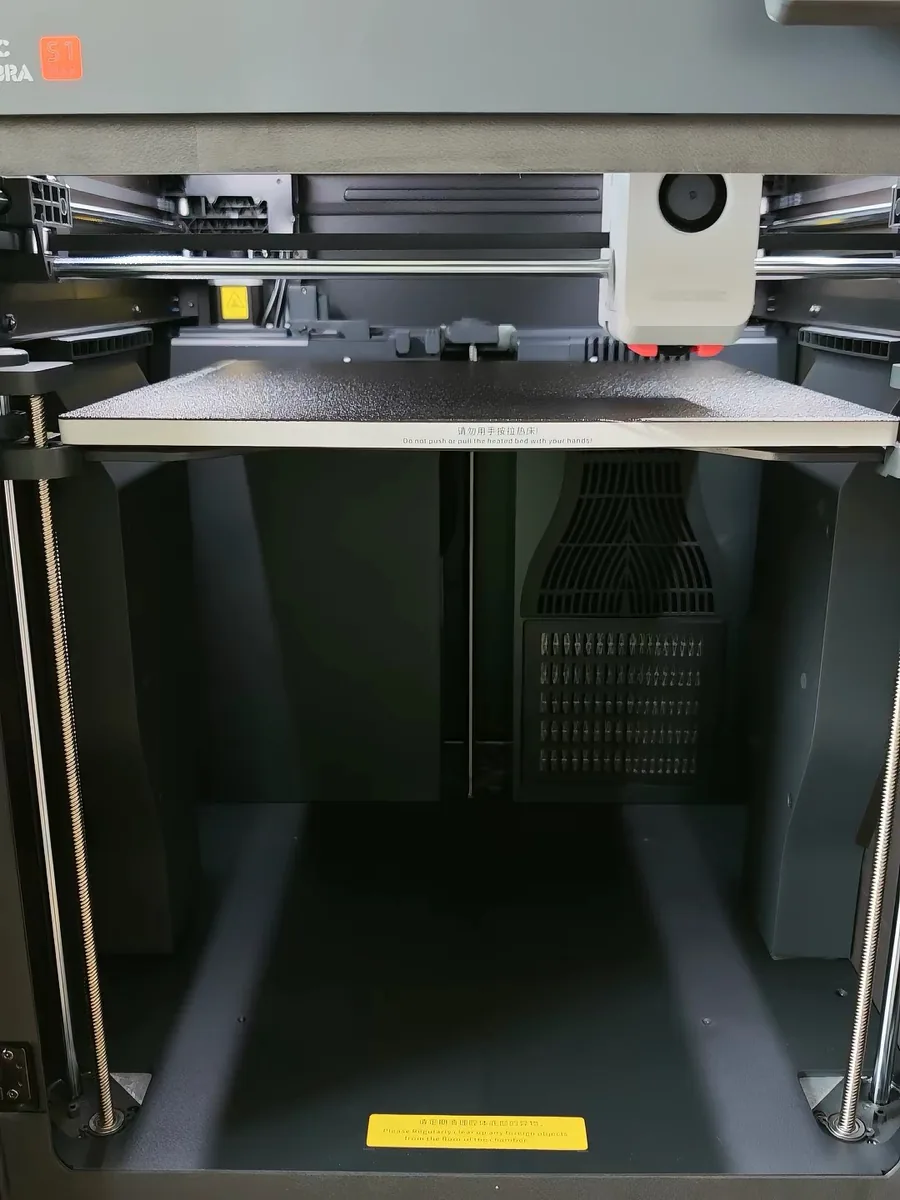 Inside the Anycubic Kobra S1 Max chamber, showing the build plate, gantry and the filter grilles along the bottom of the enclosure