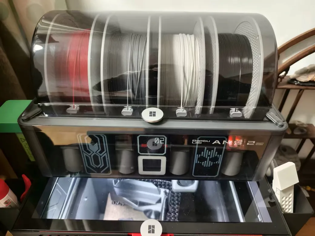 Snapmaker U1 vs Bambu Lab P2S (2026): Toolchanger Speed vs Enclosed Reliability 5 Bambu Lab AMS 2 Pro on top of the P2S with four filament spools under the clear lid and desiccant in the drying bay