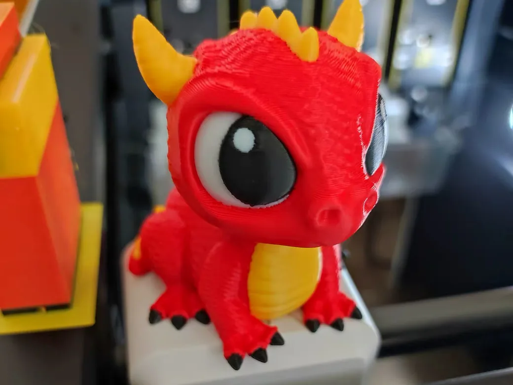 Red, yellow, black and white dragon printed on a Snapmaker U1 toolchanger, sitting on the printer's front edge