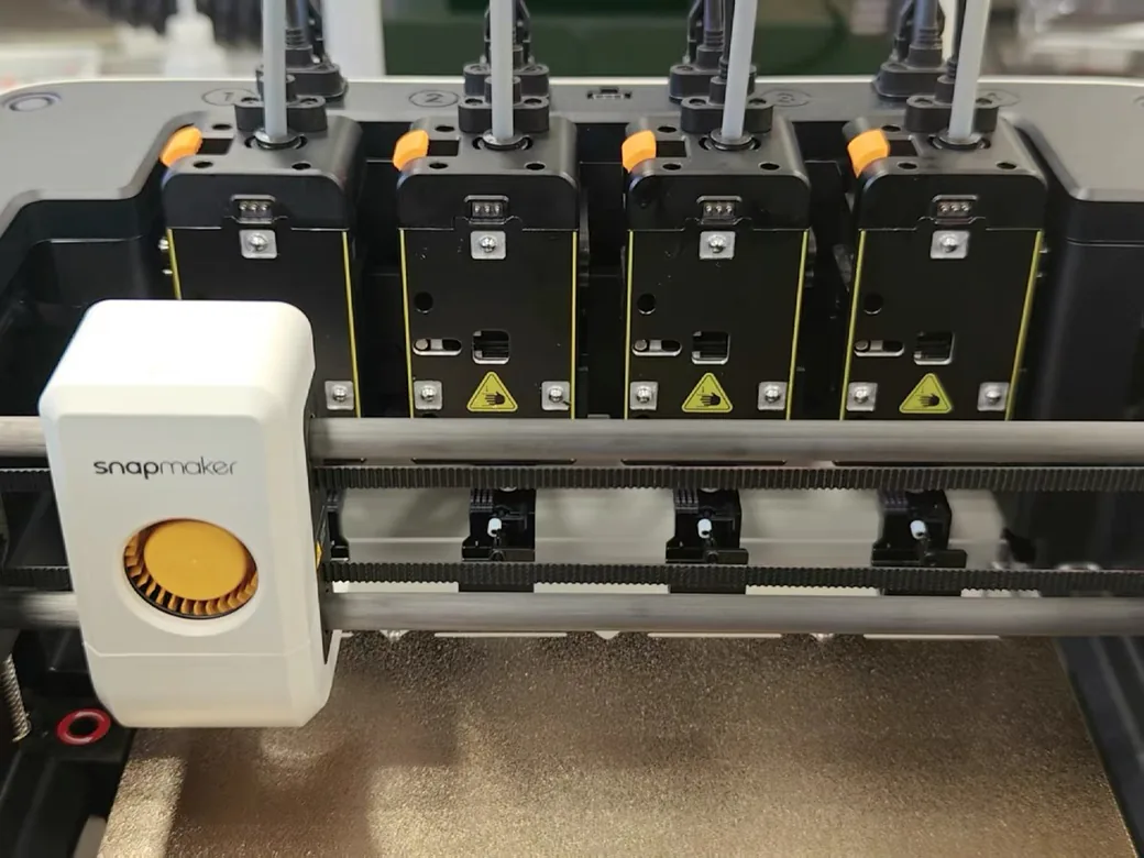 Snapmaker U1 vs Bambu Lab P2S (2026): Toolchanger Speed vs Enclosed Reliability 11 Snapmaker U1 carriage holding one toolhead beside three docked in numbered bays, with the electrical contacts visible