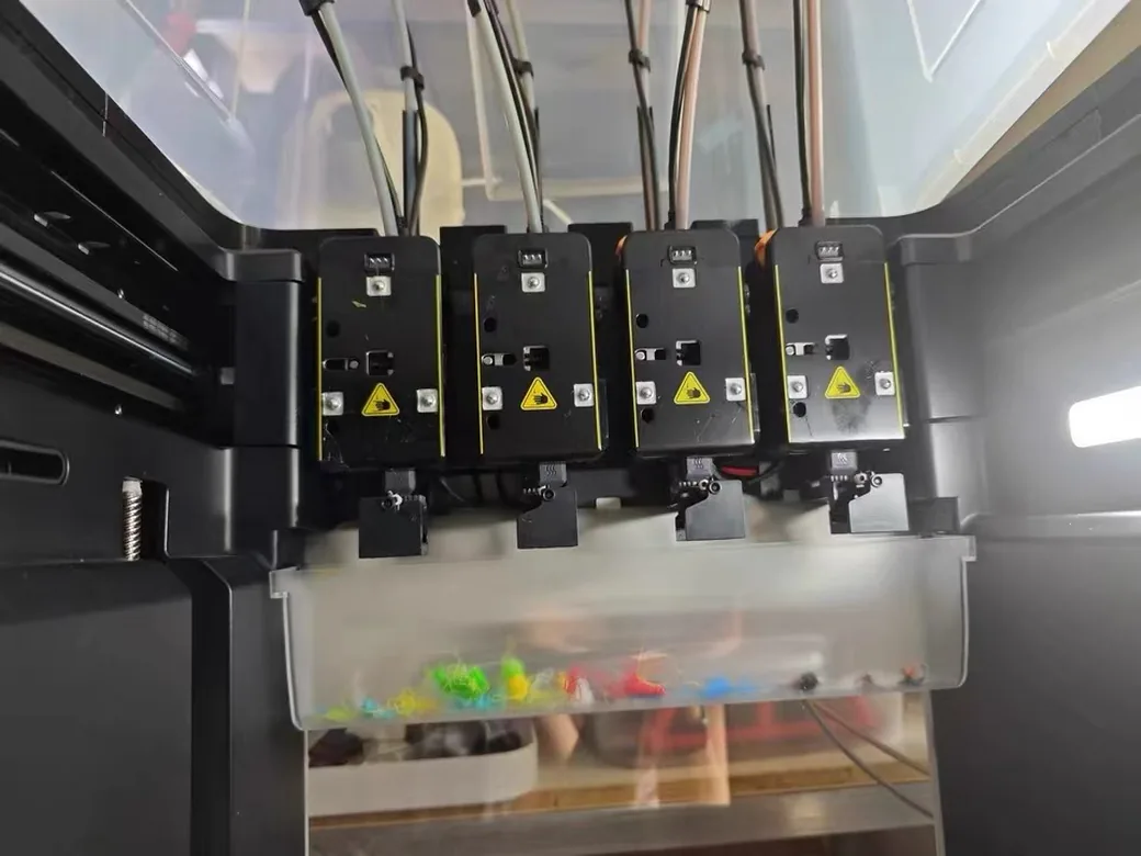 Creality K3 vs Snapmaker U1: Buy Now or Wait? (2026) 3 Snapmaker U1's four docked toolheads above the waste bin, holding a small handful of colored purge scraps
