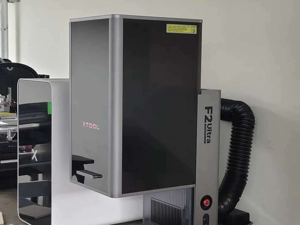 How to Choose the Best Laser Engraver/Cutter for ANY Budget 14 xTool F2 Ultra large-format laser engraver on a desk showing its glowing logo, F2 Ultra label, and emergency stop button