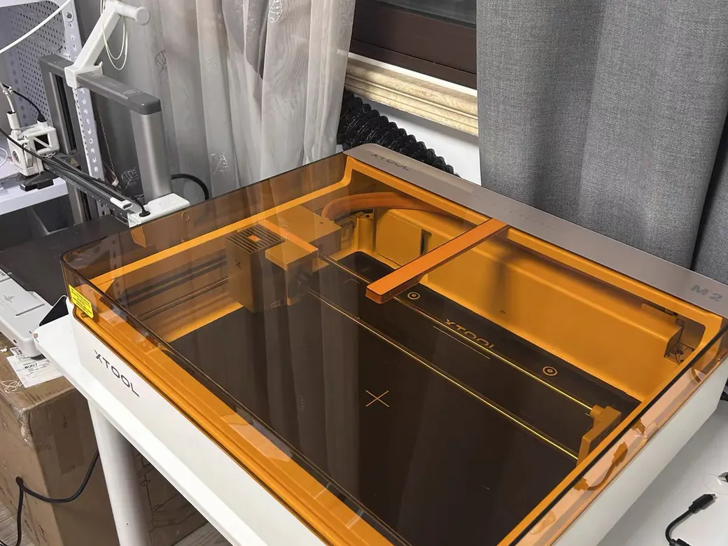 How to Choose the Best Laser Engraver/Cutter for ANY Budget 11 xTool M2 laser engraver with its lid open, showing the internal gantry and orange enclosure with XTOOL and M2 branding
