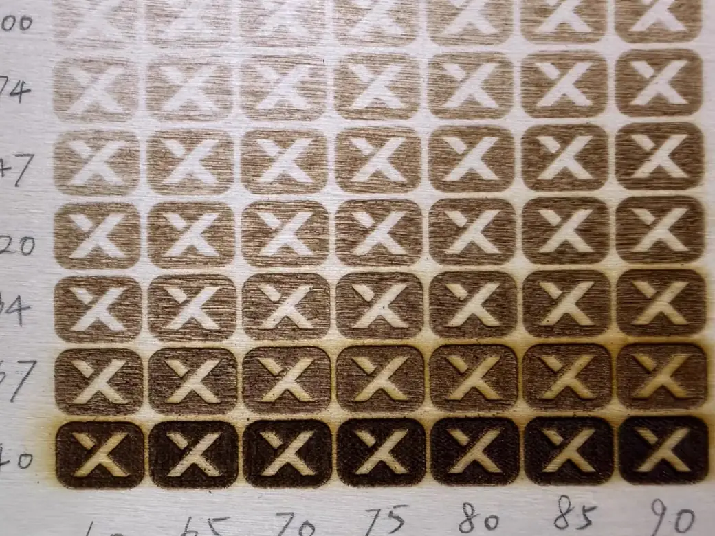 Power and speed test grid of engraved X marks on plywood, from faint to dark