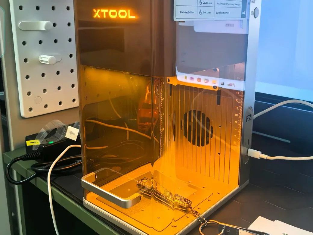 xTool F2 portable laser engraving a metal key tag on a desk