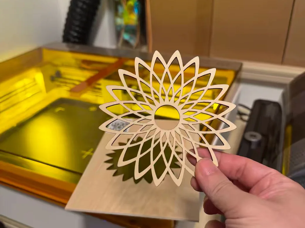 Best Laser Engraver Black Friday Deals 2026: When Sales Start and What to Pay 2 Hand holding a laser-cut wooden sunflower mandala in front of an open xTool M2